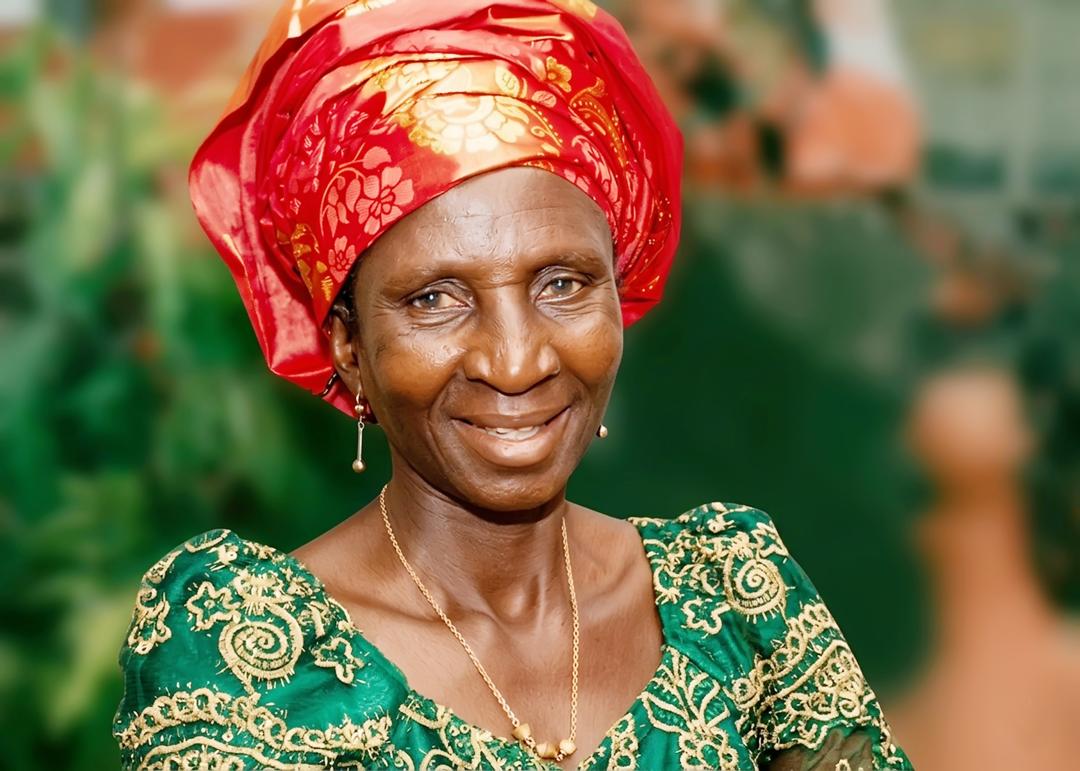 Josephine smiling in a green embroidered dress and red headwrap